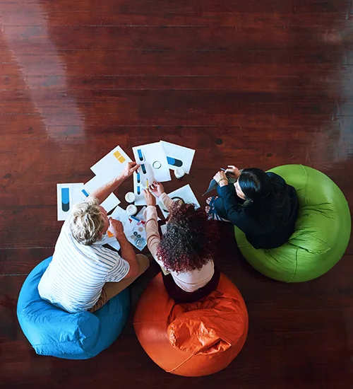 Trois collègues analysent des données, assis sur poufs ergonomiques