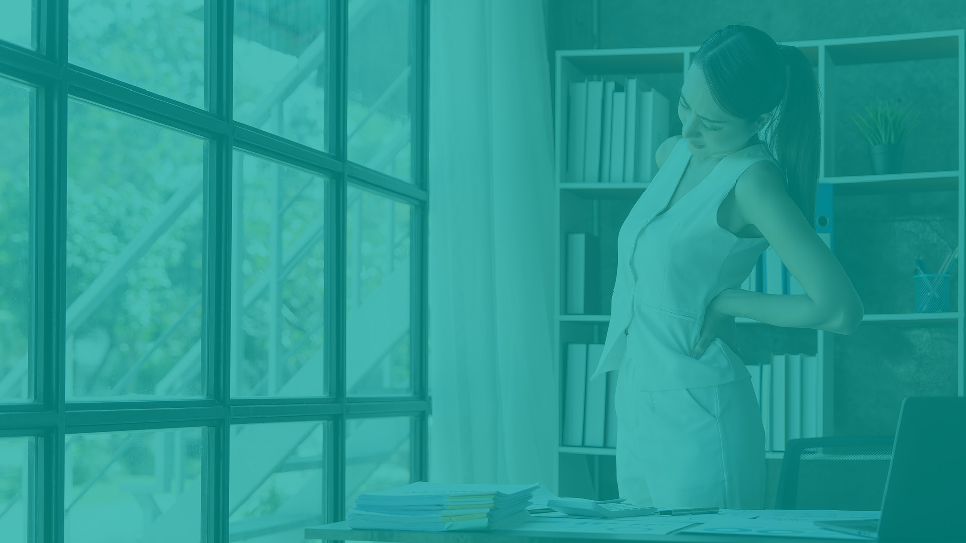 Collaboratrice en souffrance au bureau, debout et main dans le bas du dos